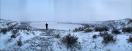 Hanna in middle distance, surrounded by sage brush, gazing across frozen fields and the Missouri river