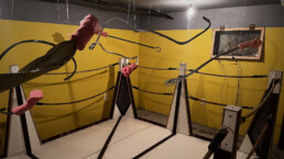 An art installation with rubber fists on cable arms suspended in a boxing ring