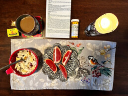 Table set for breakfast: coffee, yogurt and fruit, pills, medical instructions, and a candle
